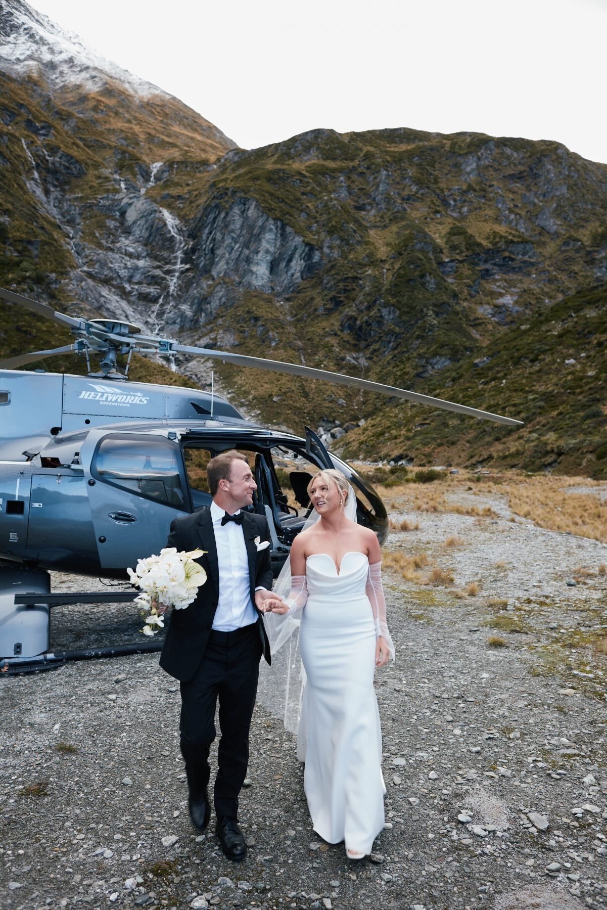 Bride and groom walking from the helicopter in the Queenstown mountains